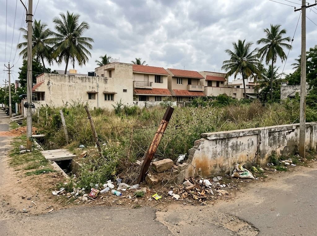 An overgrown, weed-covered vacant land plot with a leaning boundary marker, left unchecked for a long time